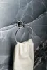 A chrome towel ring with a white towel hanging from it, mounted on a marble-like wall. Anteprima dell’immagine prodotto