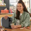 A woman is making coffee with a coffee machine in a kitchen. Produktbild-Vorschau