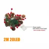 A Christmas decoration with pine cones, berries, and greenery, attached to a string of LED lights with a battery pack. Produktbild-Vorschau