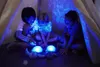 Three children are sitting inside a tent, playing with glowing turtle toys. Podgląd zdjęcia produktu