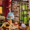 A miniature study scene with books, a lamp, a clock, and a cup of tea. Náhled obrázku produktu