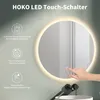 A round LED mirror with a hand touching its surface, placed above a sink with a faucet. Produktbild-Vorschau