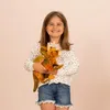A young girl is smiling and holding a stuffed triceratops dinosaur. Anteprima dell’immagine prodotto
