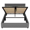 A grey upholstered bed frame with an open storage compartment, showing the wooden slatted base. Náhled obrázku produktu