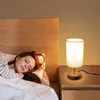 A woman sleeping in bed next to a bedside table with a lamp. Produktbild-Vorschau