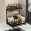 A two-tier black metal kitchen organizer shelf filled with various bottles and jars, placed on a white countertop next to a sink. Voir les images du produit