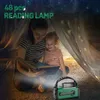 A mother and child are reading a book inside a tent, illuminated by a green lantern. Anteprima dell’immagine prodotto