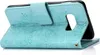 A teal flip case for a smartphone is shown open, revealing the inside of the case and the edge of a smartphone. The case has an embossed mandala pattern. Produktbild-Vorschau