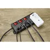 A power strip with multiple outlets and switches, along with a smart plug, is placed on a wooden surface. Produktbild-Vorschau