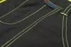 A close-up shot of black fabric with bright yellow stitching and a small brand logo. Produktbild-Vorschau