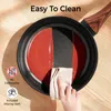 A hand is wiping a frying pan with a cloth, demonstrating its easy-to-clean feature. The pan contains some red sauce. Produktbild-Vorschau