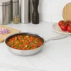 A stainless steel frying pan filled with chopped vegetables and sauce sits on a countertop next to chopped red onions, a spice jar, and tomatoes. Podgląd zdjęcia produktu