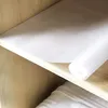A roll of white anti-slip drawer liner is placed on a wooden shelf. Voir les images du produit