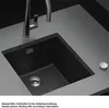 A black kitchen sink with a silver faucet and drain. Produktbild-Vorschau