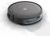 A robotic vacuum cleaner is shown from a slightly elevated angle, cleaning up scattered debris. The background is plain white. Voir les images du produit