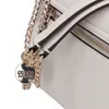A close-up of a white handbag with gold chain detailing and a Guess logo charm. Produktbild-Vorschau