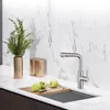 A modern kitchen sink area with a faucet, cutting board, and apples. Produktbild-Vorschau
