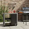 An outdoor patio scene with a grill cart and a grill, set against a brick wall with string lights. Náhľad obrázku produktu