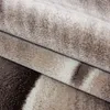 A close-up view of a folded rug with abstract patterns. Produktbild-Vorschau