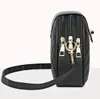 A side view of a black quilted leather crossbody bag with gold zippers against a white background. Náhled obrázku produktu