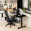A woman is working at a height-adjustable desk in a home office setting. Produktbild-Vorschau