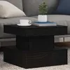 A black coffee table with a plant, books, and a cup of coffee on it, placed in a living room setting. Produktbild-Vorschau