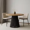 A round dining table with a slatted base and two chairs in a neutral-toned room. Produktbild-Vorschau