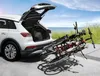 A white car with its trunk open, parked near a beach, with a bike rack attached to the back carrying two bicycles. Produktbild-Vorschau