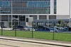 A black metal fence in front of a modern office building with cars parked in the background. Anteprima dell’immagine prodotto