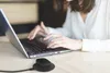 A person is using a laptop with a wireless mouse on a wooden desk. Podgląd zdjęcia produktu
