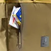 A close-up view of a zippered pocket on a brown backpack, with some items peeking out. Produktbild-Vorschau