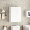 A white, modern, two-door wall cabinet is mounted on a tiled wall above a toilet in a bathroom. Náhľad obrázku produktu