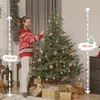 A woman decorates a Christmas tree in a room. Produktbild-Vorschau