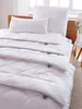 A neatly made bed with white bedding, including pillows and duvets, neatly stacked. Produktbild-Vorschau
