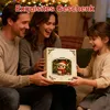 A family is happily opening a gift box with a festive owl illustration on it, likely during the Christmas season. Produktbild-Vorschau