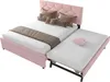 A pink upholstered bed with a pull-out trundle bed, shown with decorative pillows and a throw blanket. Anteprima dell’immagine prodotto
