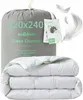 A folded duvet is shown in front of its grey fabric packaging bag, with feathers floating around. Produktbild-Vorschau