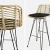 Two views of a rattan bar stool with black metal legs and a black seat cushion, presented against a plain white background. Anteprima dell’immagine prodotto