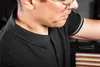 Close-up of a person wearing a black polo shirt. Produktbild-Vorschau