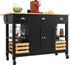 A black kitchen island with a wooden countertop, featuring drawers, cabinets, and shelves with various items like fruit, a coffee maker, bread, wine glasses, bottles, and jars. Produktbild-Vorschau