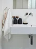 A white ceramic sink with black bathroom accessories, including a toothbrush holder and a soap dish. Produktbild-Vorschau