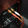 Close-up of speaker output terminals with red and white cables plugged in. Podgląd zdjęcia produktu