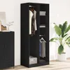A black wardrobe with clothes hanging inside and shelves with items on them, next to a tall green plant. Produktbild-Vorschau
