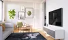 A modern living room with a TV mounted on the wall above a media console, a sofa, chairs, and decorative plants and artwork. Produktbild-Vorschau