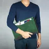A person holding a green folder with a phone and charger inside. Produktbild-Vorschau