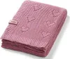 A folded pink knitted baby blanket with a heart pattern and a small tag. Produktbild-Vorschau