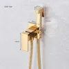 A gold-colored bidet sprayer and holder mounted on a textured gray wall, with dimensions indicated by measurement lines and text. Produktbild-Vorschau