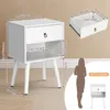 A white nightstand with dimensions shown, next to a silhouette of a person for scale. Náhled obrázku produktu