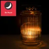 A lit glass jar with a candle inside, set against a dark background. Produktbild-Vorschau