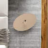 A top-down view of an oval coffee table with a vase of flowers on it, placed on a rug next to a couch and wooden flooring. Voir les images du produit